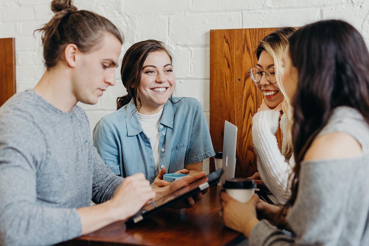 A group of teenagers smiling around a table